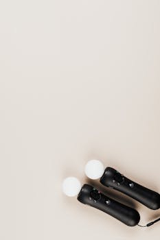 A pair of gaming controllers on a beige surface with ample copy space.