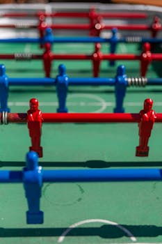 Dynamic close-up of a foosball table with red and blue figures.