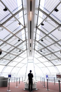 Futuristic glass-paneled architecture in an urban indoor setting with a lone figure.